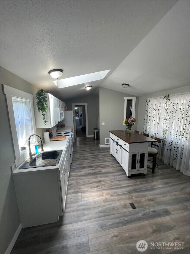 5600 Mt Solo Rd Unit 114, Longview, WA 98632 - kitchen with white cabinets, vaulted ceiling, a skylight, dark wood-style flooring, and a textured ceiling