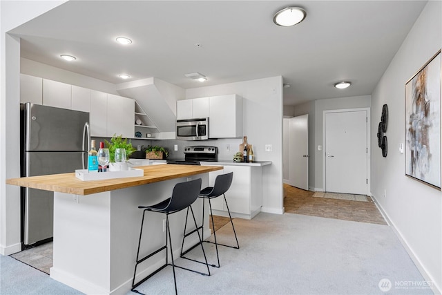 2415 2nd Ave Unit 743, Seattle, WA 98121 - kitchen featuring appliances with stainless steel finishes, butcher block countertops, a kitchen breakfast bar, light colored carpet, and open shelves