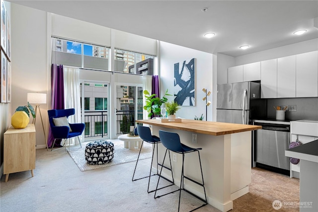 2415 2nd Ave Unit 743, Seattle, WA 98121 - kitchen featuring stainless steel appliances, butcher block countertops, a kitchen bar, white cabinets, and a kitchen island
