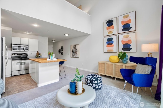 2415 2nd Ave Unit 743, Seattle, WA 98121 - kitchen with appliances with stainless steel finishes, butcher block counters, white cabinetry, a breakfast bar, and a kitchen island