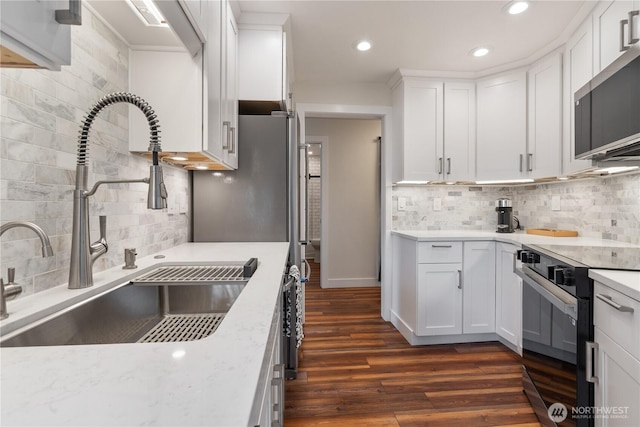 kitchen with black range with electric cooktop, a sink, backsplash, stainless steel microwave, and recessed lighting