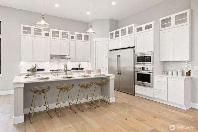 kitchen with built in appliances, under cabinet range hood, backsplash, light wood-style flooring, and recessed lighting