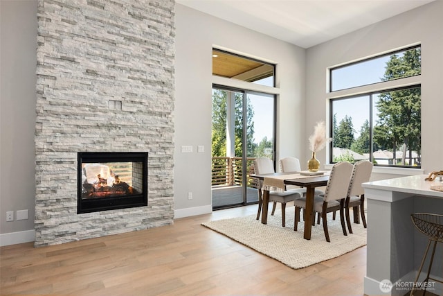 dining area with wood finished floors, baseboards, a towering ceiling, and a fireplace