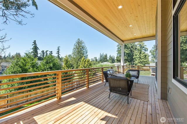 wooden terrace with outdoor lounge area and view of wooded area