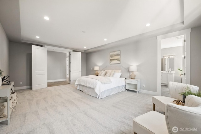bedroom with light colored carpet, recessed lighting, baseboards, and ensuite bath