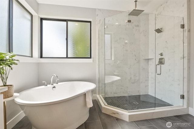 bathroom featuring a freestanding tub, a stall shower, and baseboards