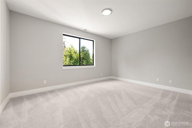 carpeted empty room featuring baseboards