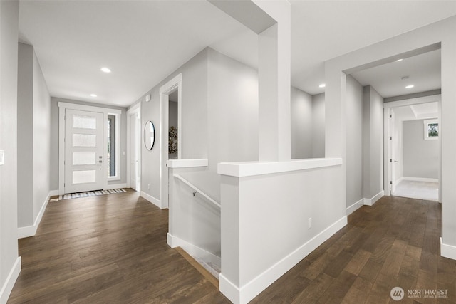 corridor featuring recessed lighting, wood finished floors, baseboards, healthy amount of natural light, and an upstairs landing