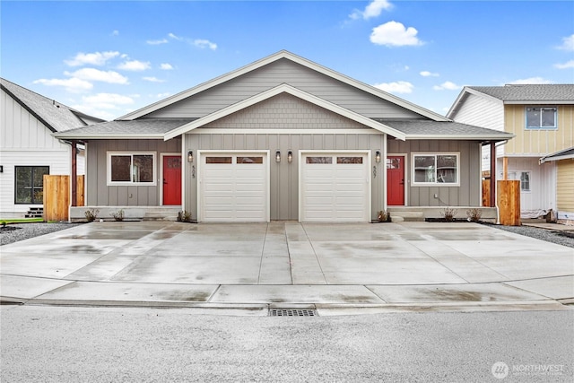 view of front facade with board and batten siding, an attached garage, driveway, fence, and a shingled roof