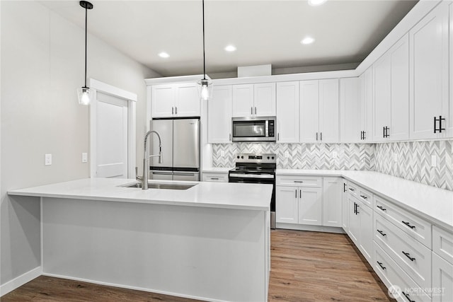 kitchen featuring stainless steel appliances, a sink, light wood-type flooring, decorative backsplash, and white cabinetry