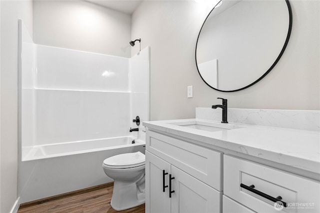 bathroom featuring wood finished floors, toilet, vanity, and shower / bath combination