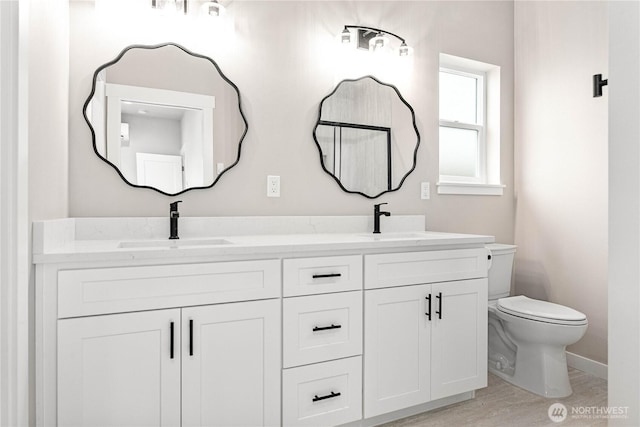 full bathroom featuring toilet, double vanity, baseboards, and wood finished floors