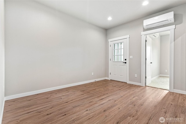 foyer with an AC wall unit, wood finished floors, recessed lighting, and baseboards