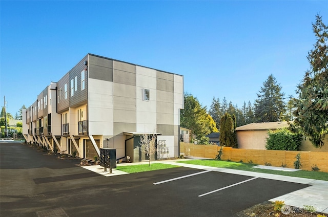 view of property featuring fence and uncovered parking