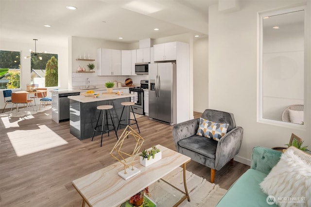 living room with light wood-style flooring, recessed lighting, a chandelier, and baseboards