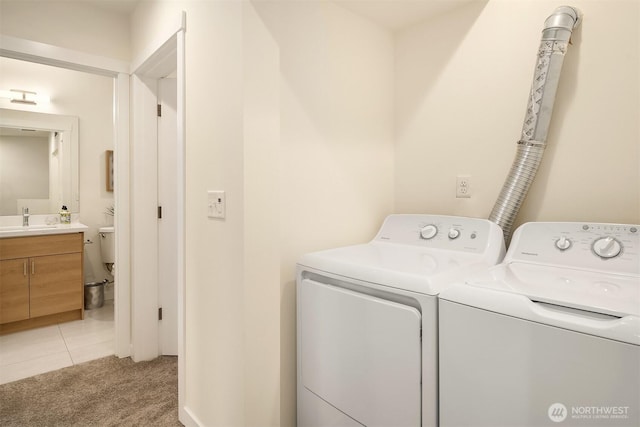 laundry room with washer and clothes dryer, light colored carpet, and light tile patterned flooring