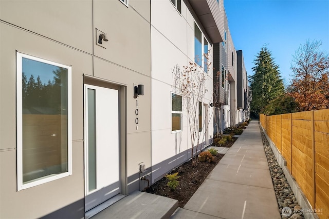 view of side of property featuring fence and stucco siding