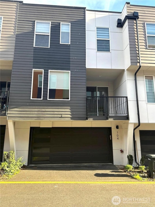 townhome / multi-family property with an attached garage, stucco siding, and a balcony