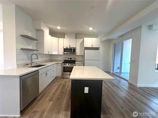 kitchen featuring appliances with stainless steel finishes, a sink, open shelves, backsplash, and dark wood finished floors