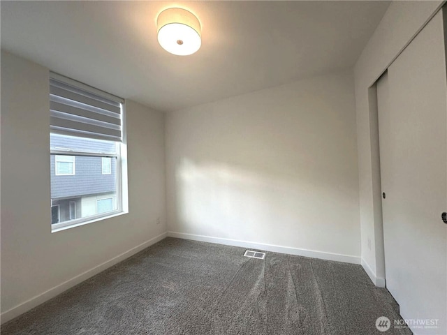 empty room featuring dark carpet and baseboards
