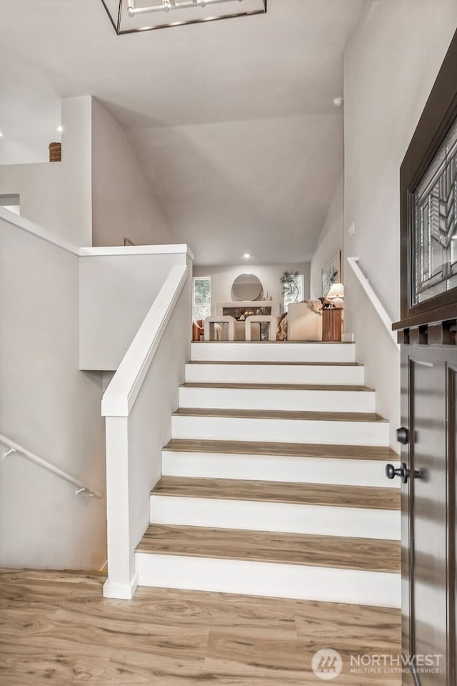 stairs featuring wood finished floors and vaulted ceiling