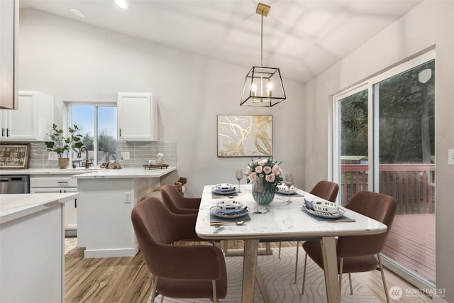 dining room with vaulted ceiling, light wood finished floors, a chandelier, and recessed lighting