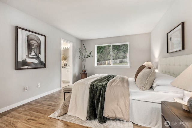 bedroom with wood finished floors, ensuite bath, and baseboards