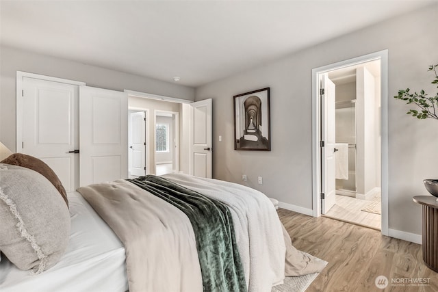 bedroom featuring baseboards, light wood-type flooring, and connected bathroom