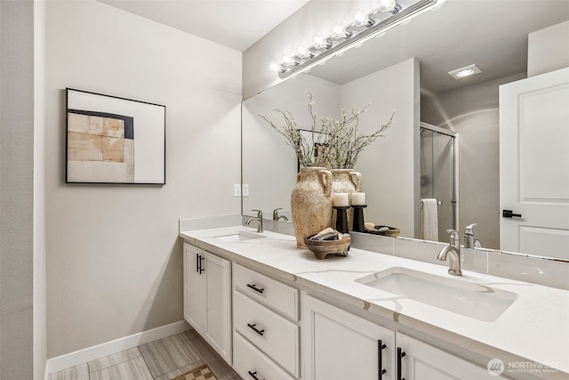 bathroom with a stall shower, double vanity, and baseboards