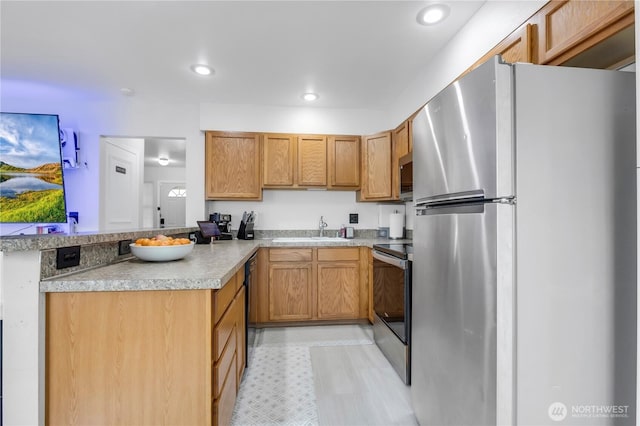 kitchen with stainless steel appliances, a sink, a peninsula, light countertops, and recessed lighting