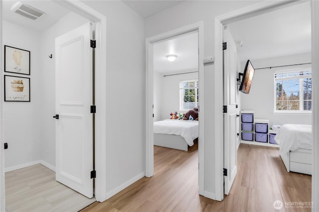 hall with light wood-type flooring and baseboards