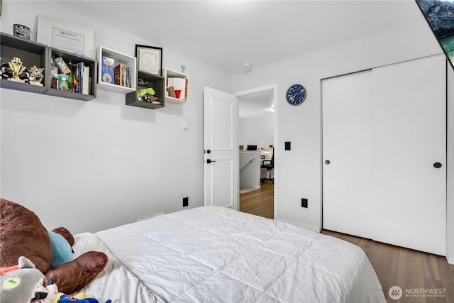 bedroom with wood finished floors and a closet