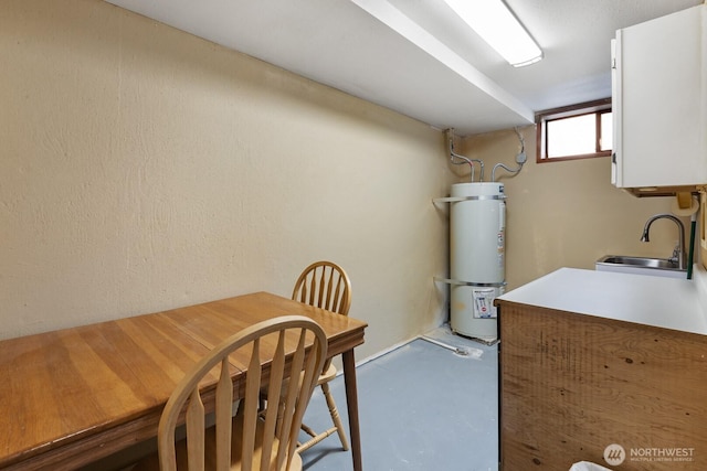 kitchen featuring strapped water heater, a sink, concrete floors, and light countertops