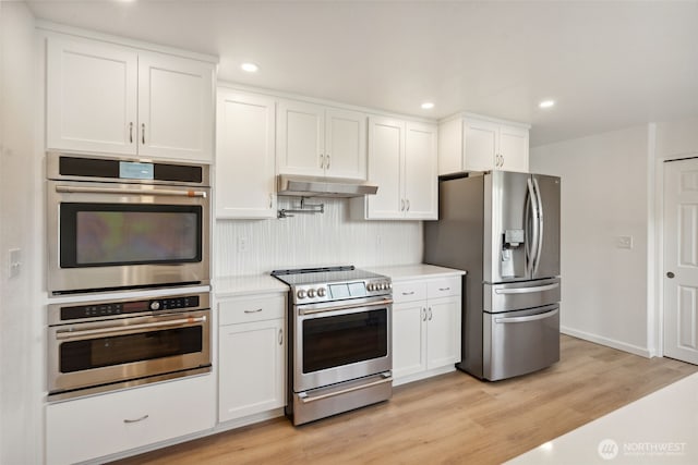 133 Bradley St, Walla Walla, WA 99362 - kitchen with appliances with stainless steel finishes, under cabinet range hood, light countertops, light wood-type flooring, and white cabinets