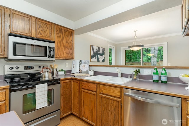 16007 NE 40th Ct Unit 1A, Redmond, WA 98052 - kitchen featuring appliances with stainless steel finishes, a sink, brown cabinetry, crown molding, and hanging light fixtures
