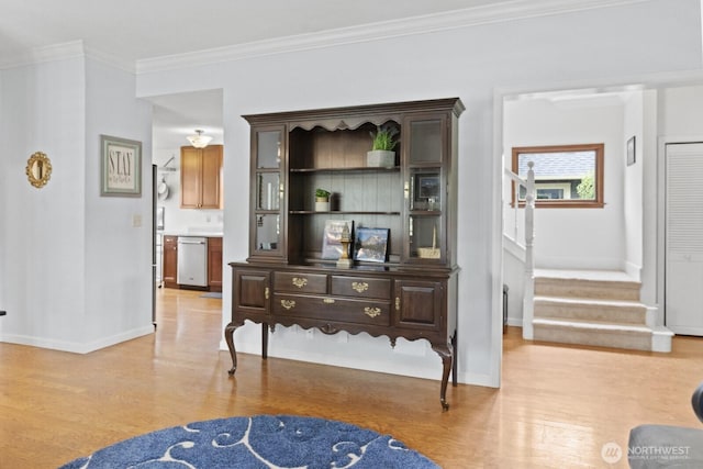 hallway with light wood-style flooring, stairs, ornamental molding, and baseboards