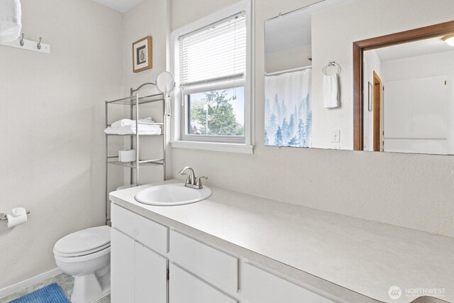 full bath featuring toilet, vanity, a shower with shower curtain, and baseboards