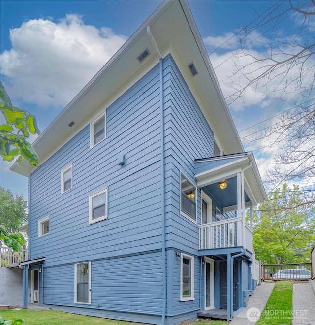 view of property exterior featuring a balcony and fence