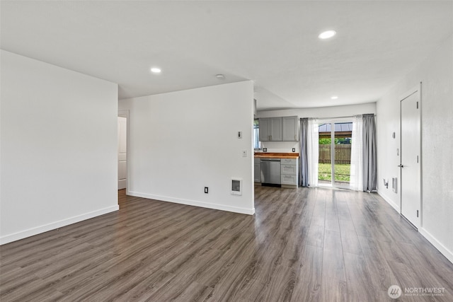 unfurnished living room with dark wood finished floors, recessed lighting, and baseboards