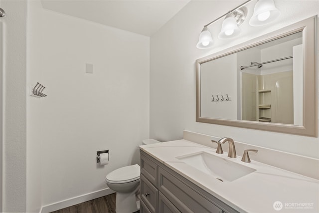 full bathroom featuring wood finished floors, toilet, vanity, baseboards, and a shower