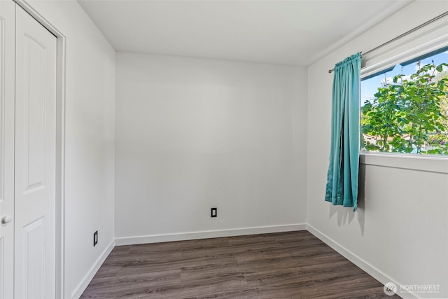 unfurnished room with dark wood finished floors and baseboards