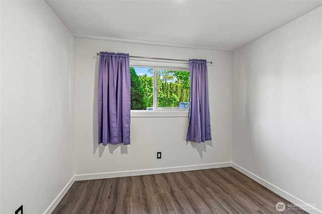empty room featuring dark wood-style flooring and baseboards