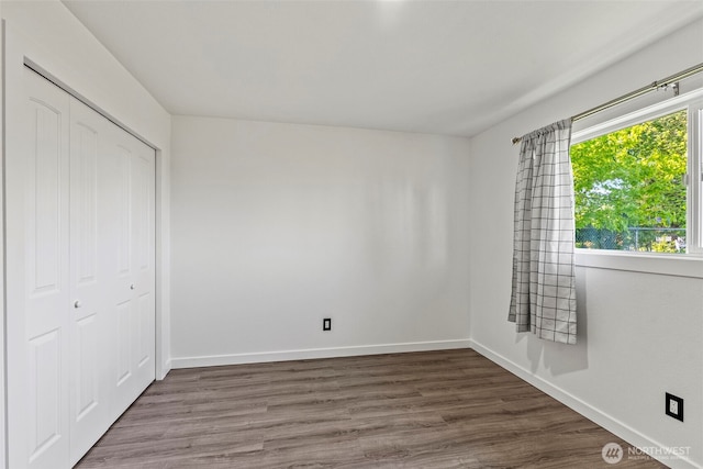 unfurnished bedroom featuring baseboards, a closet, and wood finished floors