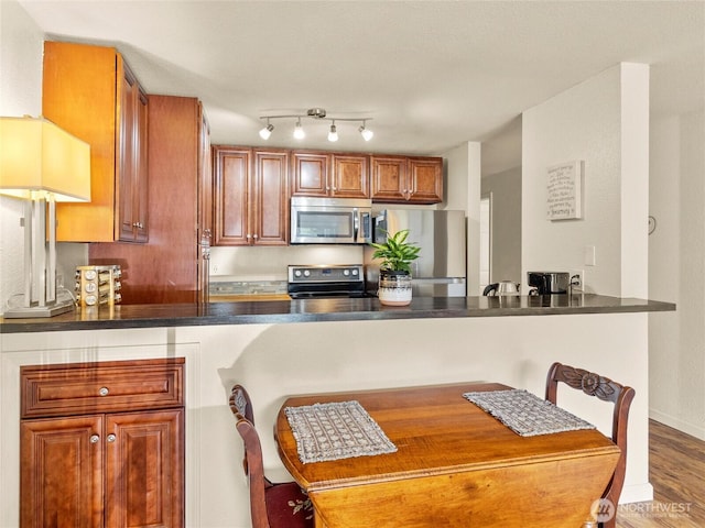 31003 14th Ave S Unit H1, Federal Way, WA 98003 - kitchen featuring appliances with stainless steel finishes, a peninsula, dark countertops, wood finished floors, and brown cabinets