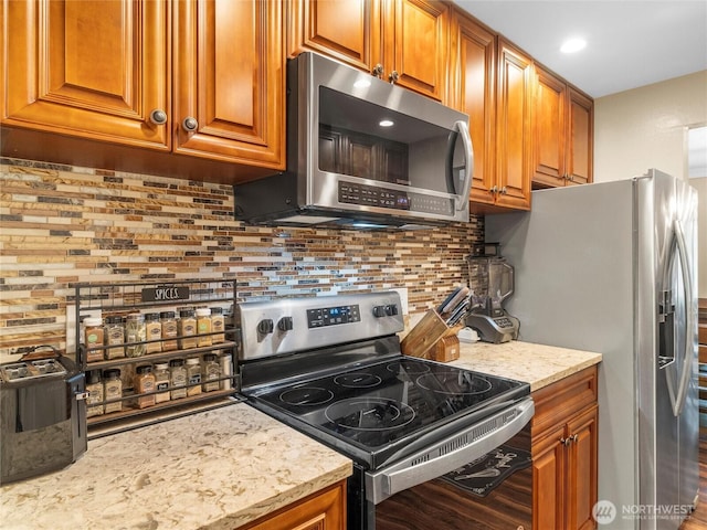 1420 153rd Ave NE # 4004, Bellevue, WA 98007 - kitchen with stainless steel appliances, brown cabinets, decorative backsplash, and light stone counters