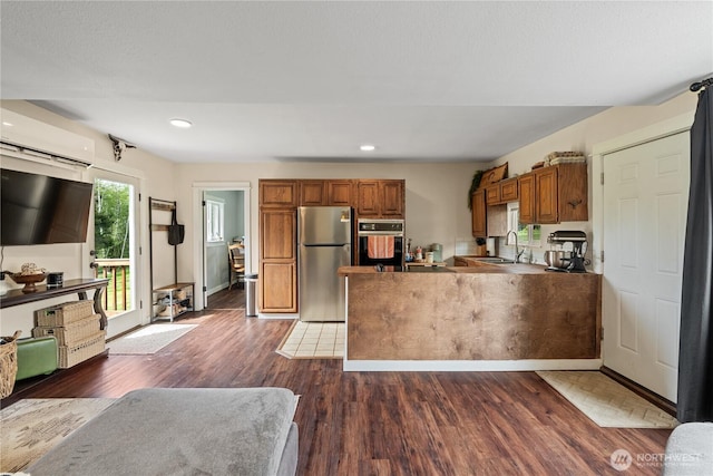 85 Rustemeyer Rd, Aberdeen, WA 98520 - kitchen with stainless steel appliances, an AC wall unit, brown cabinets, a sink, and dark wood finished floors