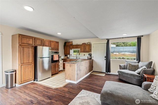 85 Rustemeyer Rd, Aberdeen, WA 98520 - kitchen featuring freestanding refrigerator, black oven, a peninsula, open floor plan, and wood finished floors