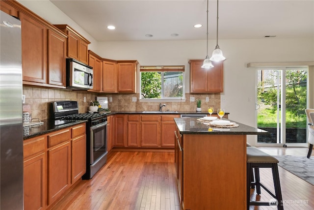 4135 240th Pl SE, Bothell, WA 98021 - kitchen featuring stainless steel appliances, a sink, light wood-style flooring, a kitchen island, and a kitchen bar