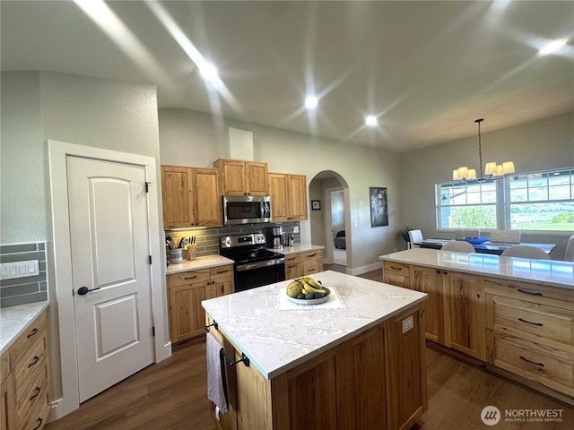 22 Rooster Flats Rd, Oroville, WA 98844 - kitchen with appliances with stainless steel finishes, arched walkways, a center island, tasteful backsplash, and dark wood-style flooring
