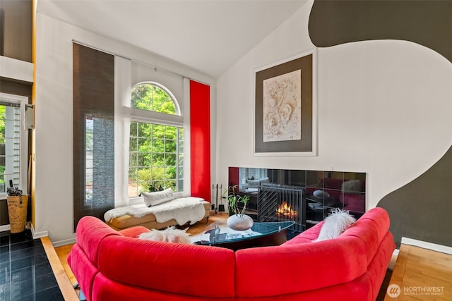 living room with a tile fireplace, vaulted ceiling, wood finished floors, and baseboards
